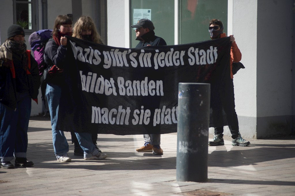 Demo gegen AfD in Flensburg, Transparent mit Aufschrift Nazis gibs in jeder Stadt. Bildet Banden. Macht sie platt. Davor vermummte Personen. Nordermarkt. Aufnahme vom 11.04.2026, Flensburg